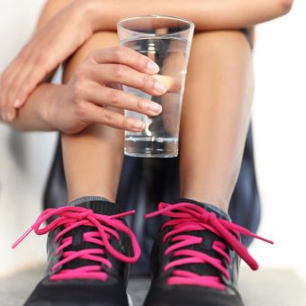 Fitness athlete woman drinking water holding glass – hand closeu