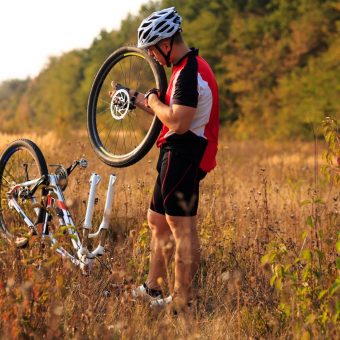 Man cyclist repairing a bike  against green nature