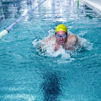 Fit man swimming with swimming hat in swimming pool