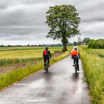 Bicycling on rainy weather near green fields outdoor