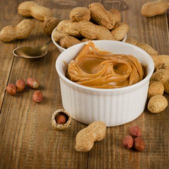 Peanut Butter With Peanuts On A Rustic Wooden Table.