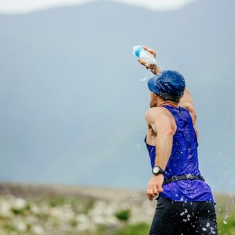 running male athlete spray face of bottle with water