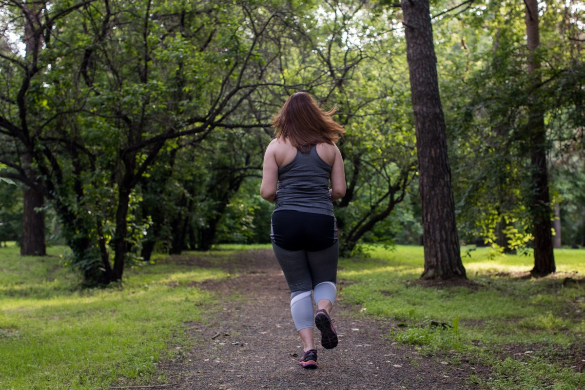 Overweight woman back running in the park . Weight loss concept.