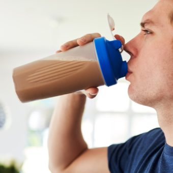 Man Drinking Protein Shake In Kitchen At Home